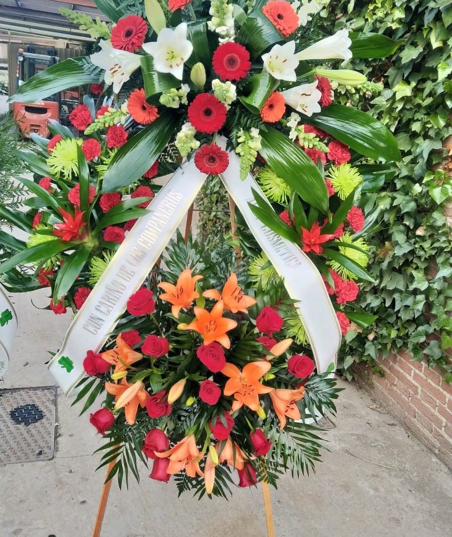 corona funeraria con flores rojas y naranjas hechas por Floristería De Tomás