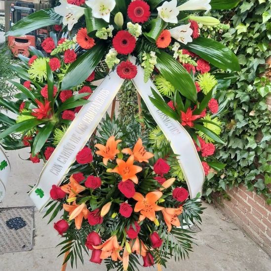 corona funeraria con flores rojas y naranjas hechas por Floristería De Tomás
